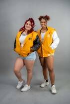 Classic Varsity Jacket 49 Two women wearing Reign Gear yellow and white water-repellent hooded varsity jackets.