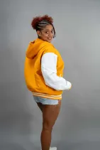Classic Varsity Jacket 31 Reign Gear women's yellow and white hooded varsity jacket modeled against a gray background